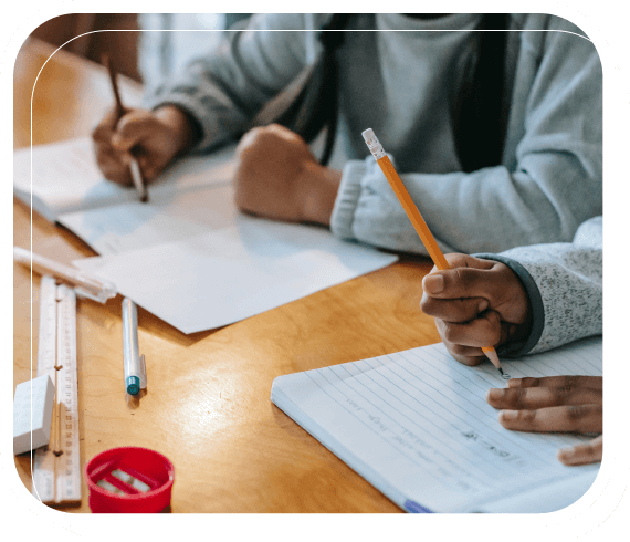 Students writing in notebooks at their classroom desk